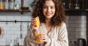 A person with glowing, radiant skin holding a Kinnow or drinking Kinnow juice